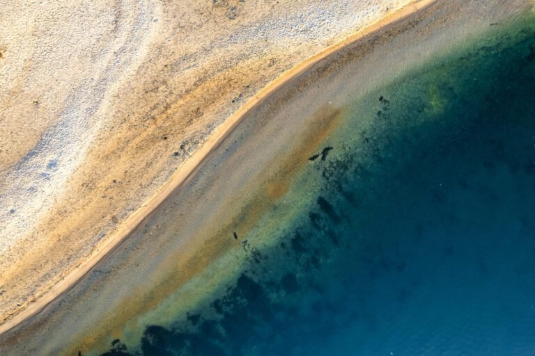 A stunning aerial shot showcasing a pristine beach meeting the deep blue ocean, with vibrant sandy textures.